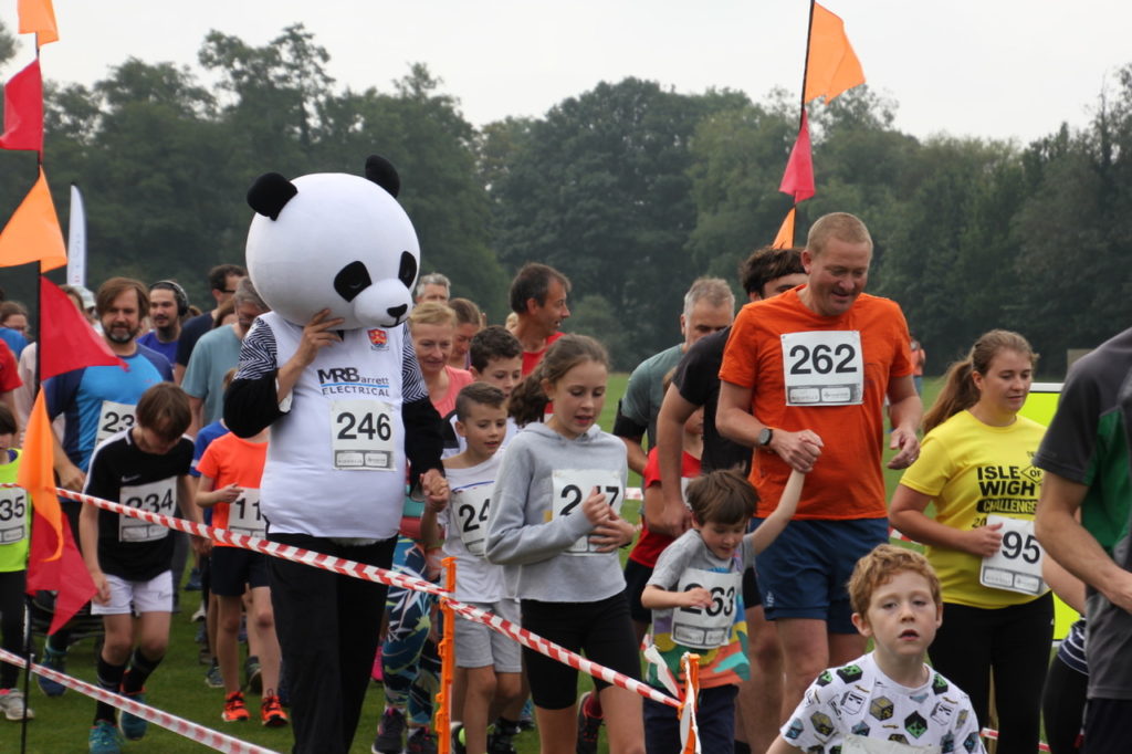 Children, adults and a person dressed as panda at the startling of the Fun Run
