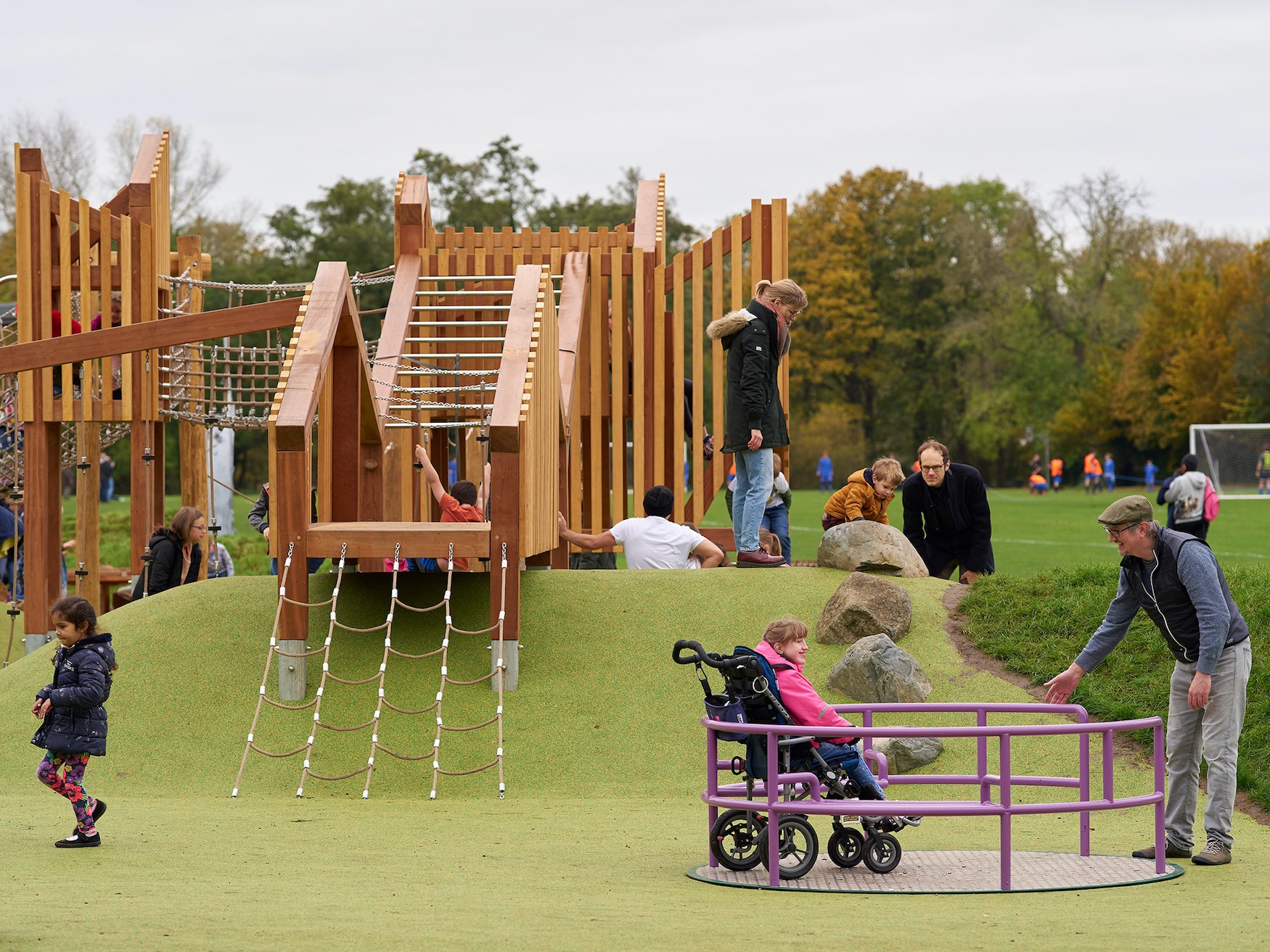 Photo of Shelford Playscape with the roundabout in the foreground and wooden climbing frame beyond